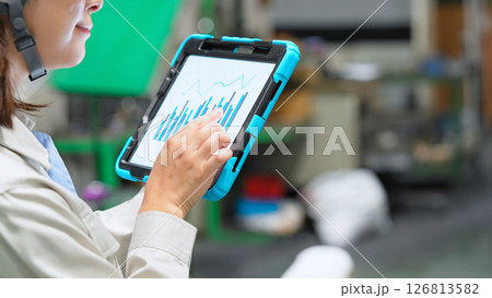 タブレットを持って工場機械を点検する女性作業員 126813582