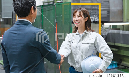 工場で握手する男性ビジネスパーソンと女性作業員 工場で握手する男性ビジネスパーソンと女性作業員 126813584