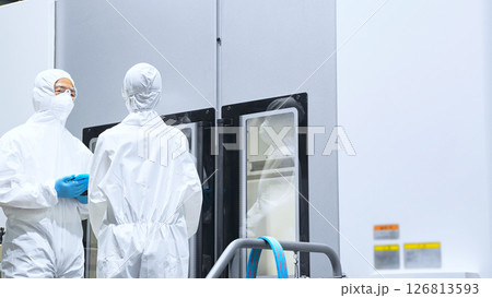 工場機械を操作する防護服を着た男女作業員 126813593