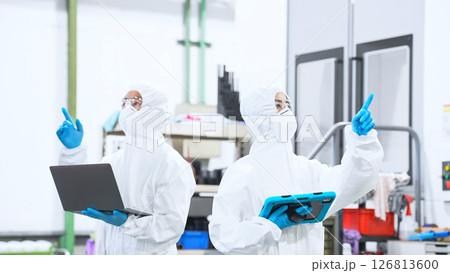 デジタルデバイスを持って工場で作業する防護服を着た男女作業員 126813600