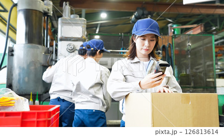 工場でハンディターミナルを使って製品を検査する女性作業員 126813614
