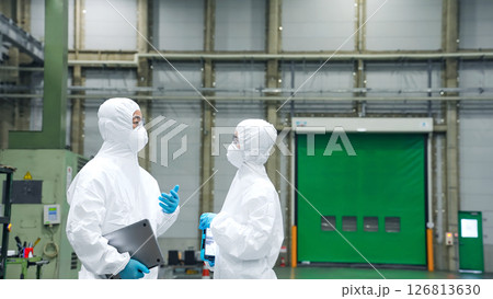 防護服を着て工場の中で話す男女作業員 126813630