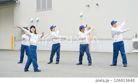 工場の前で体操する作業員グループ 126813648