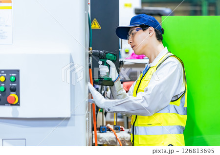 工場で工作機械のメンテナンスをする作業員 126813695