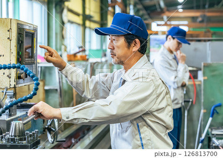 工場で機械を操作する男性作業員 工場で機械を操作する男性作業員 126813700