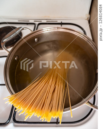 spaghetti is dropped into pot of boiling water 126814084