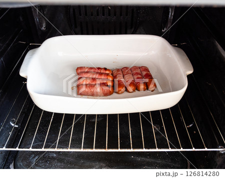 portion of sausages wrapped in bacon in gas oven 126814280