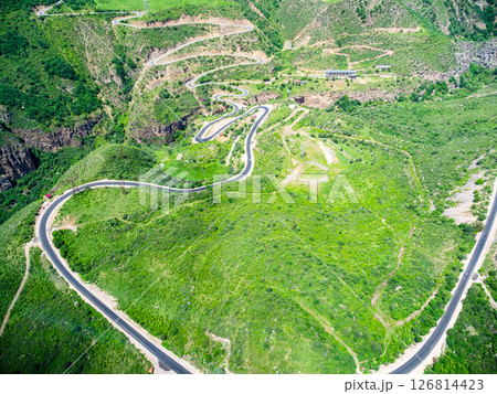 aerial view of green plateau with serpentine road 126814423
