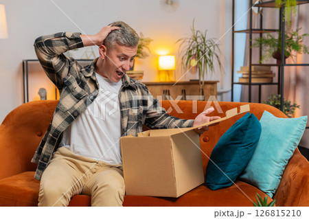Happy customer man unpacking delivery parcel opening cardboard box receiving purchase gift at home Happy customer man unpacking delivery parcel opening cardboard box receiving purchase gift at home 126815210