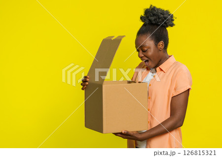 Black woman unboxing delivery package, excited expression, online shopping gift, quick service Black woman unboxing delivery package, excited expression, online shopping gift, quick service 126815321
