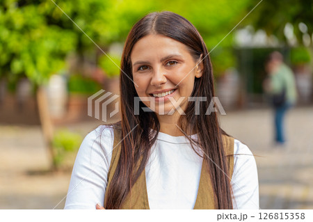 Portrait of smiling brunette young woman friendly glad expression looking at camera on city street 126815358