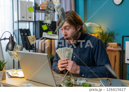 Rich businessman celebrate win on laptop earnings profit success win lottery money cash rain falling 126815627
