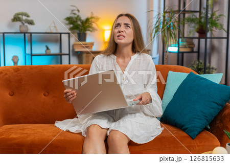 Upset young Caucasian woman using laptop computer having anxiety and stress sitting on sofa at home 126815633