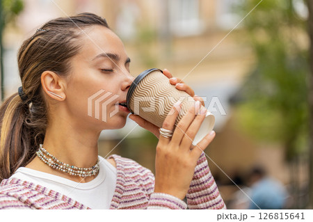 Happy smiling woman walking on city street enjoying morning coffee hot drink relaxing taking a break 126815641