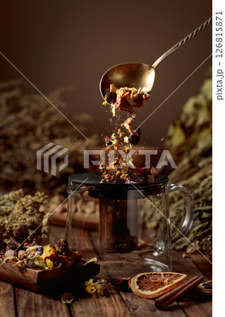 Various dried herbs and spices is poured into a glass teapot. Various dried herbs and spices is poured into a glass teapot. 126815871