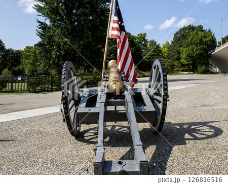 Historic Cannon Displayed Outdoors With American Flag on a Clear Day 126816516