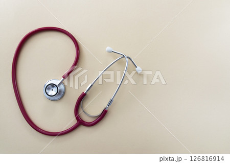 Red stethoscope on beige background with space for text. Medical instrument. Health care concept. 126816914