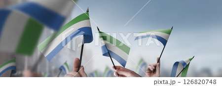 Sierra Leone flags in their hands on a blurred urban background 126820748