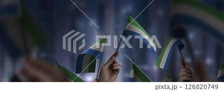 Sierra Leone flags in their hands on a blurred urban background Sierra Leone flags in their hands on a blurred urban background 126820749