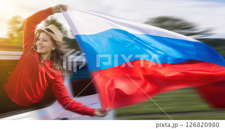 Woman celebrating Russia Day while waving the Russian flag during her travel trip. A woman in a red jacket celebrates Russia Independence Day 126820980