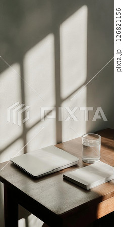 Glass table with notebook and water, sunlight shadow pattern background 126821156