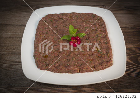 Delicious Lebanese Kebbe Naye garnished with olive oil and fresh mint on a rustic wooden table Delicious Lebanese Kebbe Naye garnished with olive oil and fresh mint on a rustic wooden table 126821332