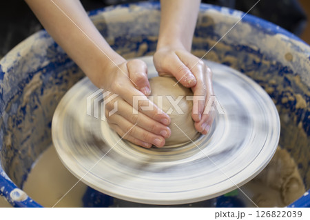 Potter's hands at work. Close-up of a potter's hands with a product on a potter's wheel. Working with clay. Potter's hands at work. Close-up of a potter's hands with a product on a potter's wheel. Working with clay. 126822039