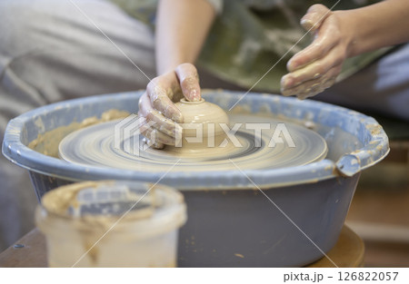 Close-up of a potter's hands with an item on a potter's wheel. Working with clay. Clay workshop. Craft training. Close-up of a potter's hands with an item on a potter's wheel. Working with clay. Clay workshop. Craft training. 126822057