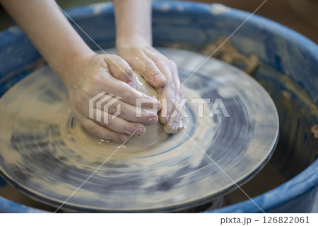 Close-up of a potter's hands with an item on a potter's wheel. Working with clay. Clay workshop. Craft training. Close-up of a potter's hands with an item on a potter's wheel. Working with clay. Clay workshop. Craft training. 126822061