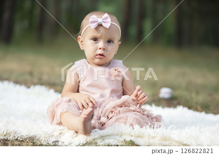 A beautiful little girl on a walk in a summer park. One year old child. Sweet baby. 126822821