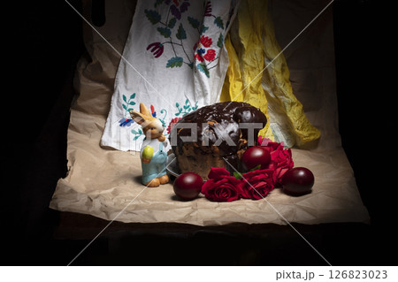 Beautiful Easter background. Chocolate cake with colored eggs and an Easter bunny on the background of an embroidered shirt. Beautiful Easter background. Chocolate cake with colored eggs and an Easter bunny on the background of an embroidered shirt. 126823023