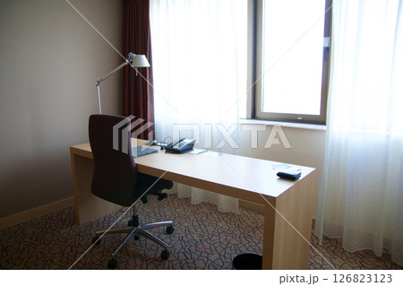 Mainz, Germany, July 7, 2017: Hotel Room Desk with Telephone, Lamp, and Chair by the Window 126823123