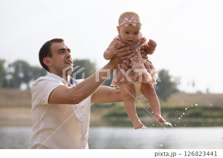Happy dad throws up with his little daughter for a walk. Paternity. 126823441