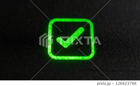 Bright green illuminated check mark inside square icon on black textured surface for approval or success symbol 126823786