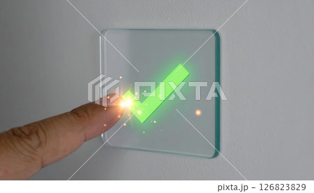 Person tapping on transparent touchscreen sensor device with green checkmark symbol for successful confirmation or approval 126823829