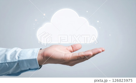 Person holding a glowing cloud icon in hand with digital effects and a clean background, technology concept 126823975