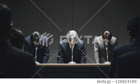 謝罪記者会見で頭を下げるスーツのビジネスマンたち 126824180
