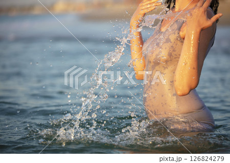 A woman in a T-shirt sprays sea water. Swimming in the ocean. 126824279