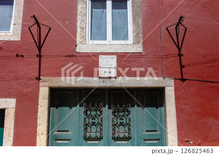 Building facade with a teal door and intricate ironwork in a red building. Building facade with a teal door and intricate ironwork in a red building. 126825463