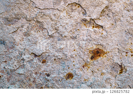 Background of a light beige metal wall from which layers of hardened cement mortar are peeling off, and the exposed areas are covered with brown, deep rust. Properties of structural materials 126825782