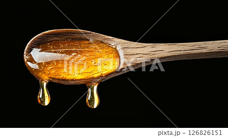 Golden Honey Dripping from Rustic Wooden Spoon on Black Background Golden Honey Dripping from Rustic Wooden Spoon on Black Background 126826151
