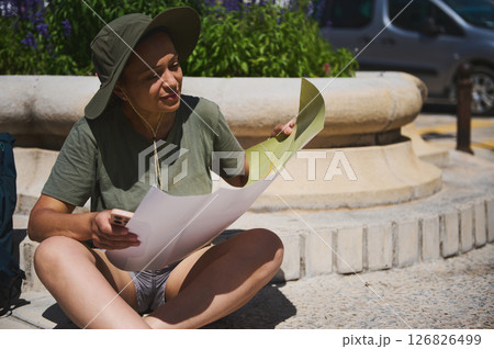 Traveler Sitting Outdoors Exploring a Map on a Sunny Day 126826499