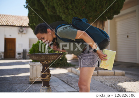 Traveler Exploring a Historic Spanish Village by Quenching Thirst at a Public Fountain Traveler Exploring a Historic Spanish Village by Quenching Thirst at a Public Fountain 126826500