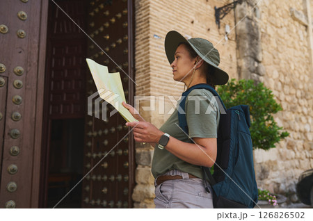 Traveler Exploring Historic Medieval City with Map and Backpack on Sunny Day Traveler Exploring Historic Medieval City with Map and Backpack on Sunny Day 126826502