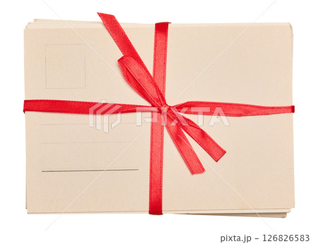 A stack of blank postcards tied with a red ribbon and bow, isolated background. 126826583