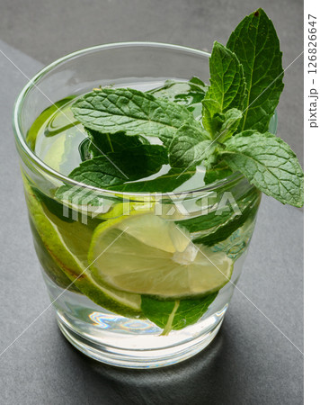 Refreshing mojito cocktail with lime, mint, and ice on dark background Refreshing mojito cocktail with lime, mint, and ice on dark background 126826647