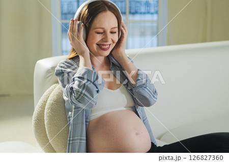 Pregnancy motherhood. Pregnant woman listening music for mother and unborn baby at home. Girl in headphones enjoying pregnancy listen music for relax healthy zen calm peace wellness, Maternity concept 126827360