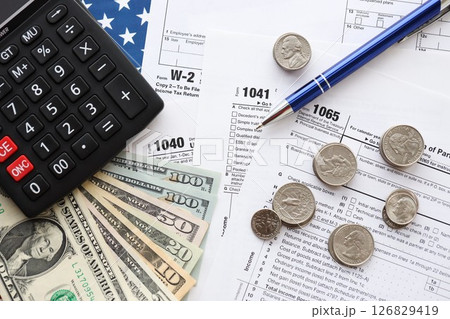 American US dollars money bills and coins with pen and calculator on IRS tax form blanks 126829419