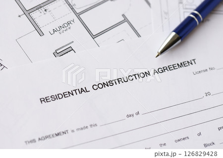 Pen on residential construction agreement and planning blueprints of residential building project 126829428