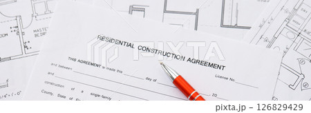 Pen on residential construction agreement and planning blueprints of residential building project 126829429